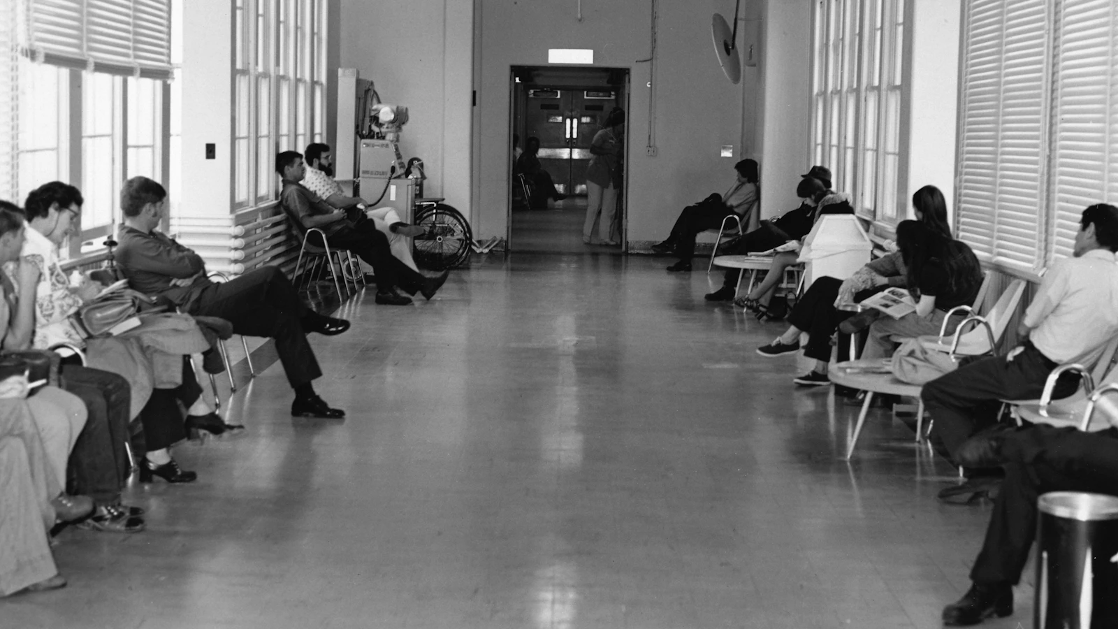 Sala de espera de posto de saúde com pacientes aguardando atendimento presencial
